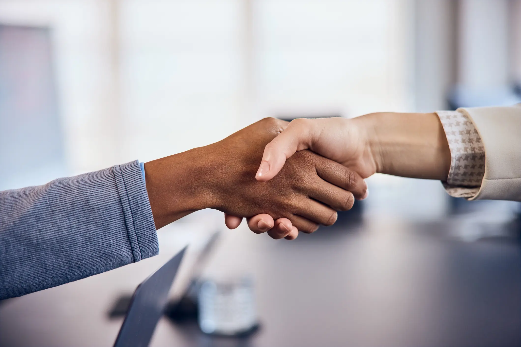 Two people shaking hands in a business setting.